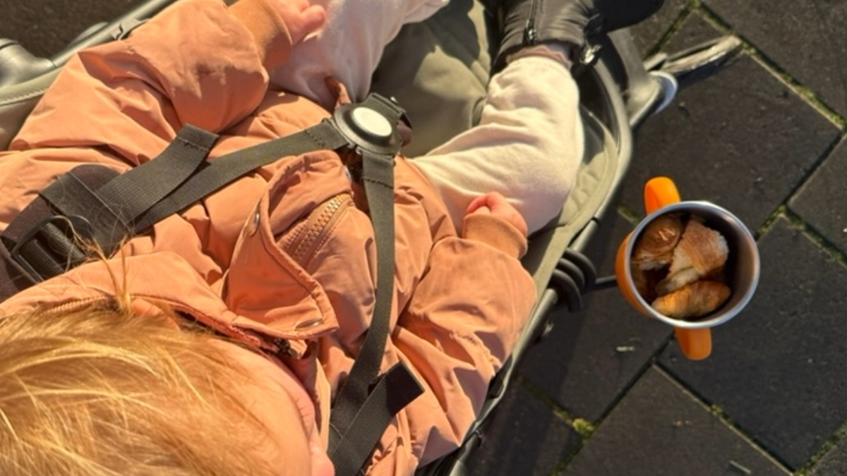 Snack cup with cut up croissants and toddler in a stroller