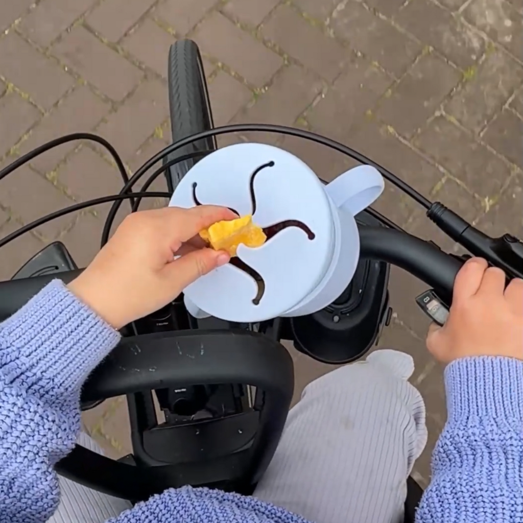 toddler reaching into a snack cup hile riding a bicycle