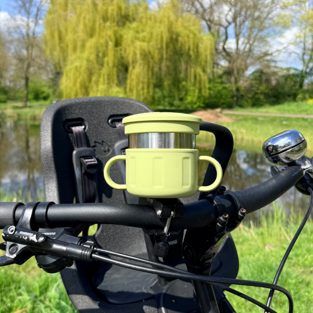 green snack cup mounted to a bicycle handlebar with a natural background