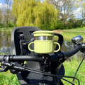 green snack cup mounted to a bicycle handlebar with a natural background