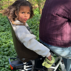child on a bike reaching into a snack cup that is mounted to the bicycle