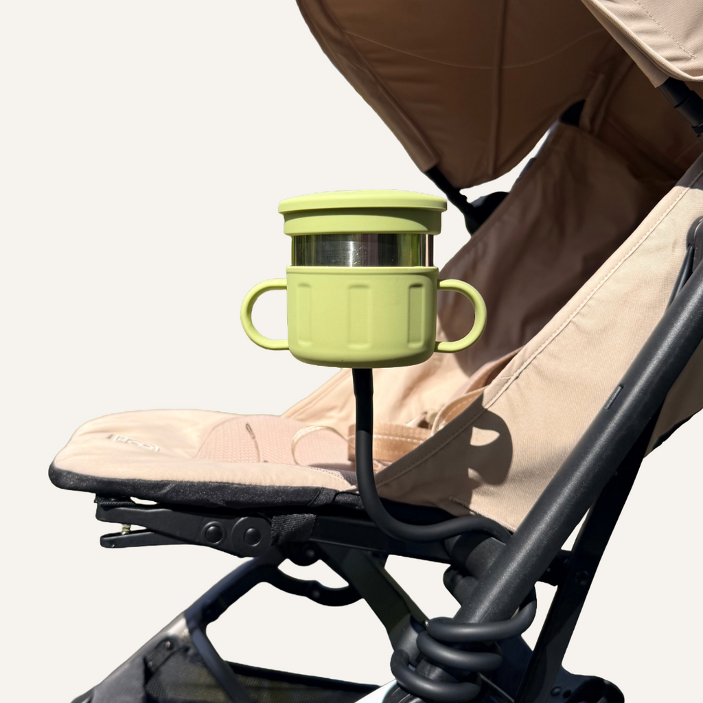 Green snack cup attached to a stroller on a white background