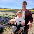 Man and child on a bike in a field of flowers with a mounted snack cup